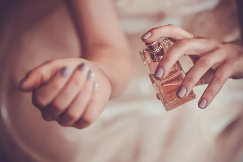 Woman applying fragrance to wrist